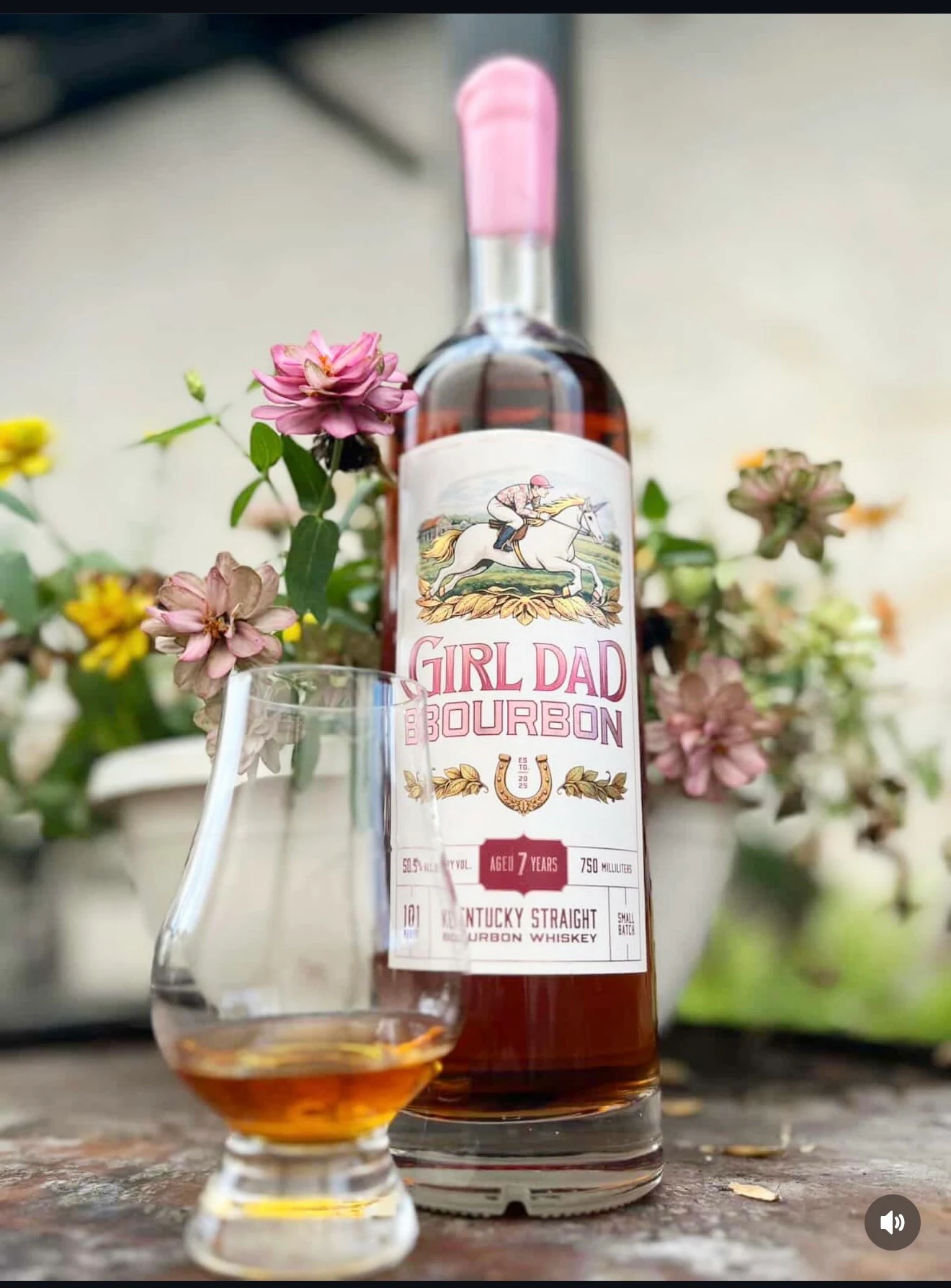 Girl Dad Bourbon bottle with a straight pink wax seal beside a tasting glass and flowers