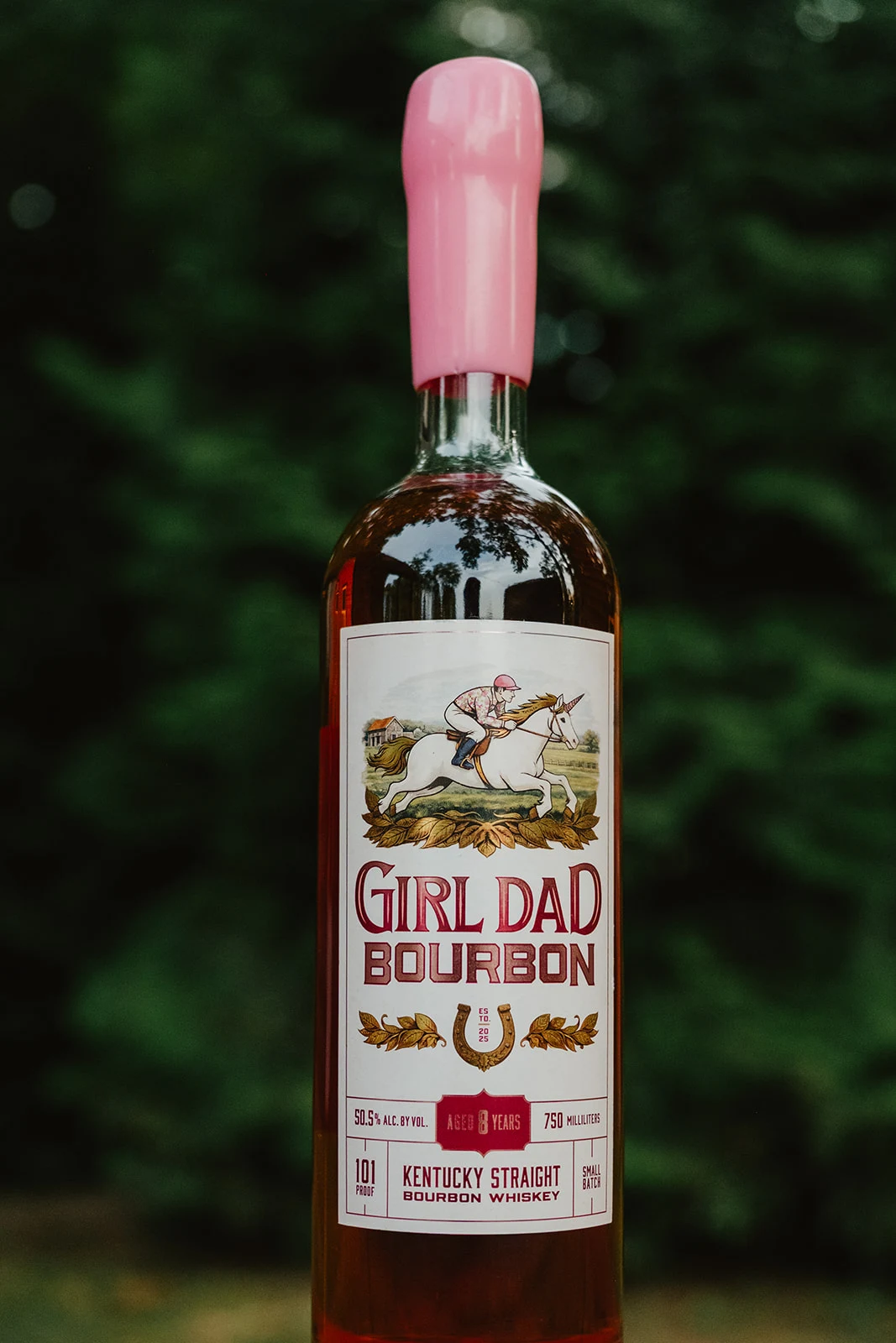Girl Dad Bourbon 8-year bottle with its signature pink wax seal against green foliage